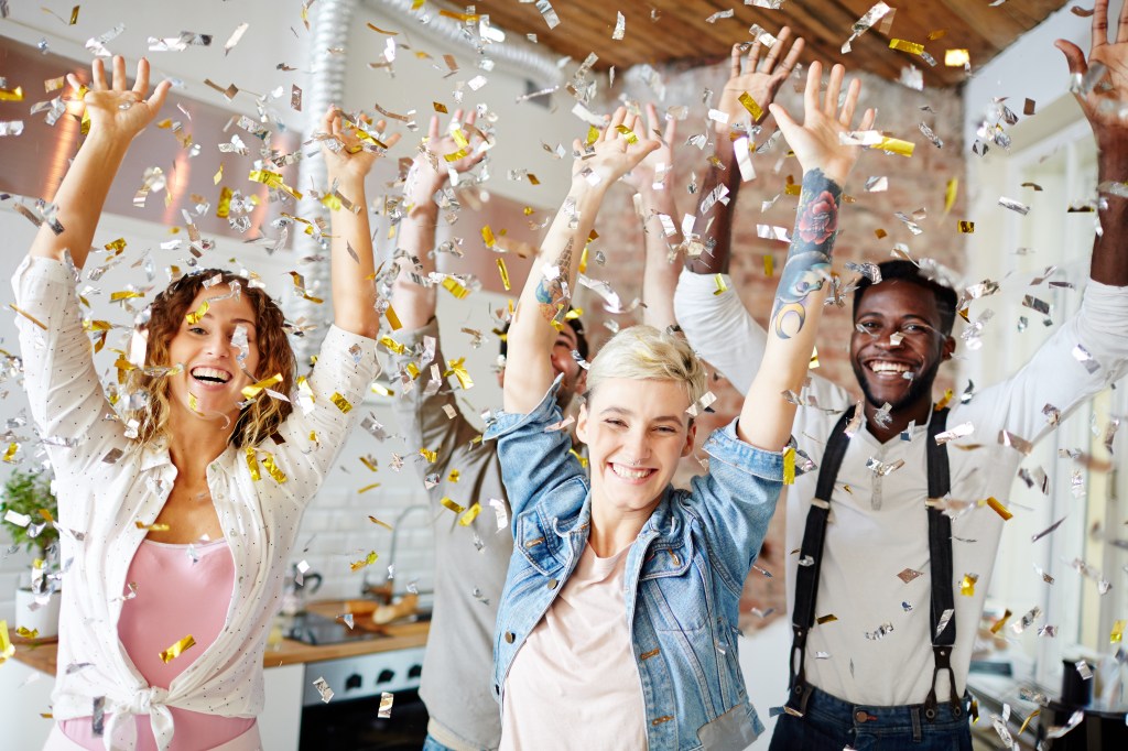 Young cheerful teenagers in casualwear dancing at xmas party under confetti rain