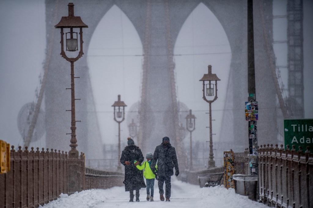 People walk down the Brooklyn Bridge during a snow storm on Saturday, Jan. 29, 2022, in New York. 