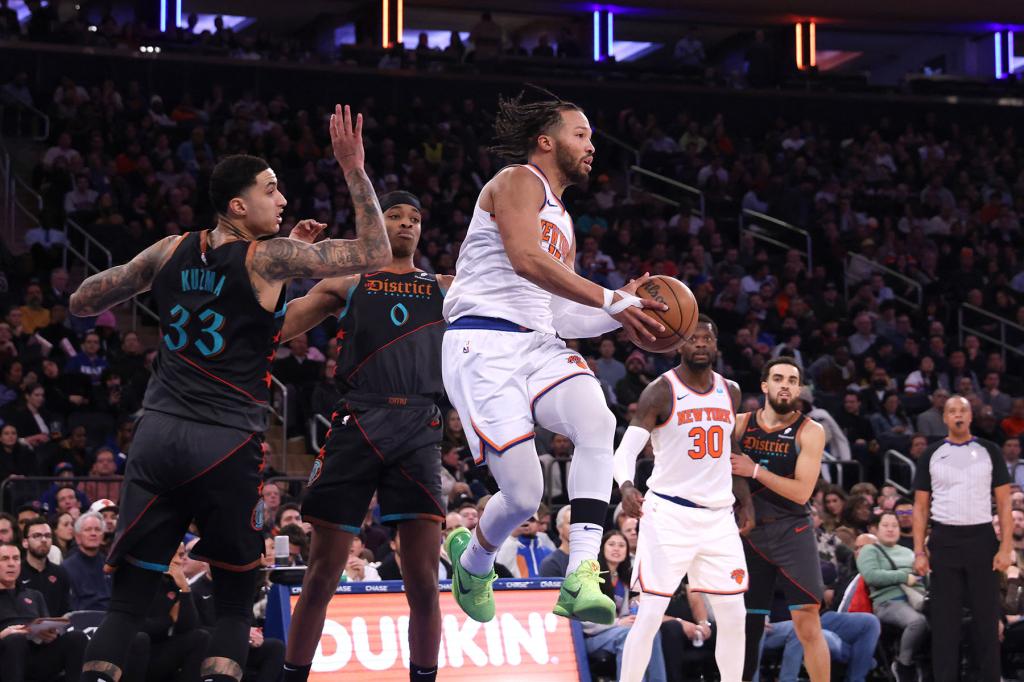 New York Knicks guard Jalen Brunson #11 makes a jumping pass as Washington Wizards forward Kyle Kuzma #33 and Washington Wizards guard Bilal Coulibaly #0 defend under the basket during the fourth quarter. The New York Knicks defeated the Washington Wizards 113-109.