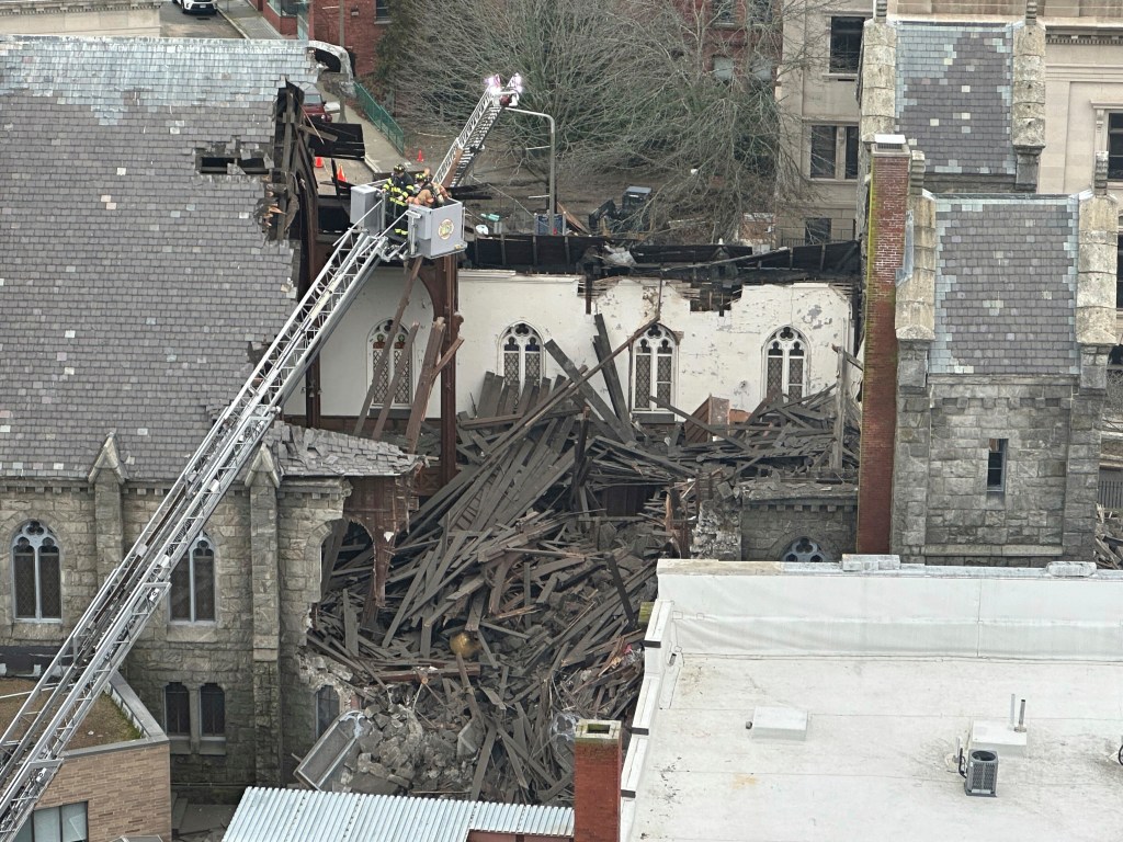 Historic church with missing stone steeple, roof damage, and debris on the ground.