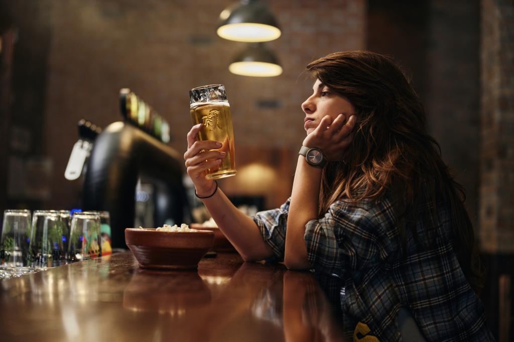 Depressed woman drinking beer alone at the bar. 