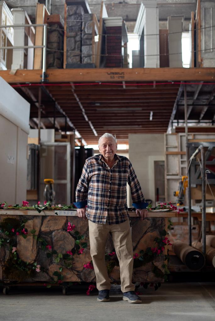 Stephen DeMaria in front of a stone and flower counter in a construction workshop. 