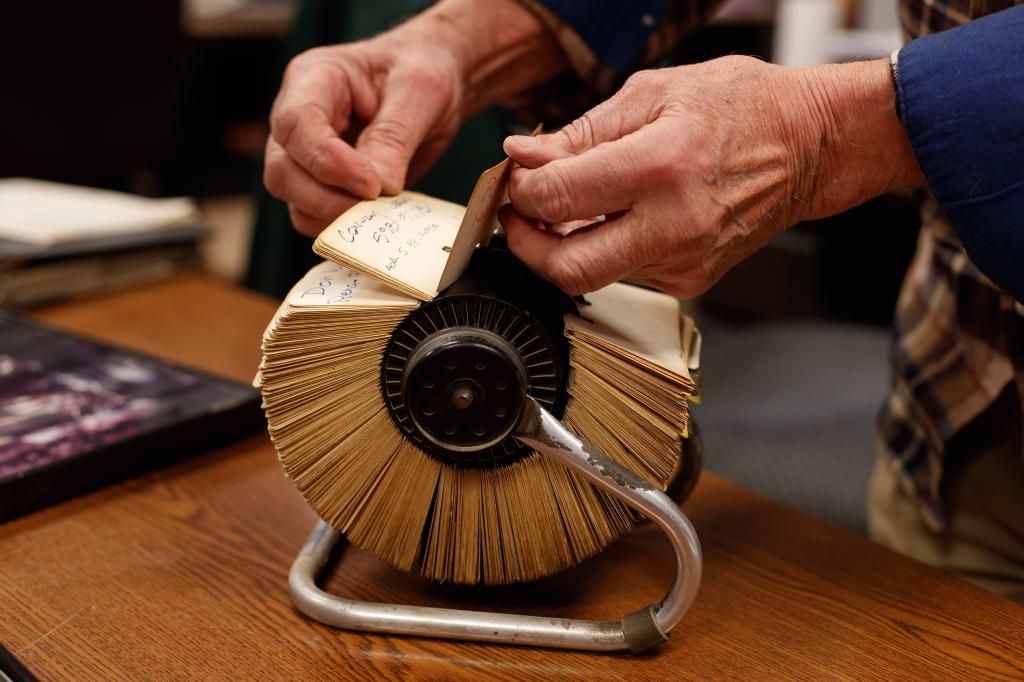 Close up hands flipping through an old Rolodex. 