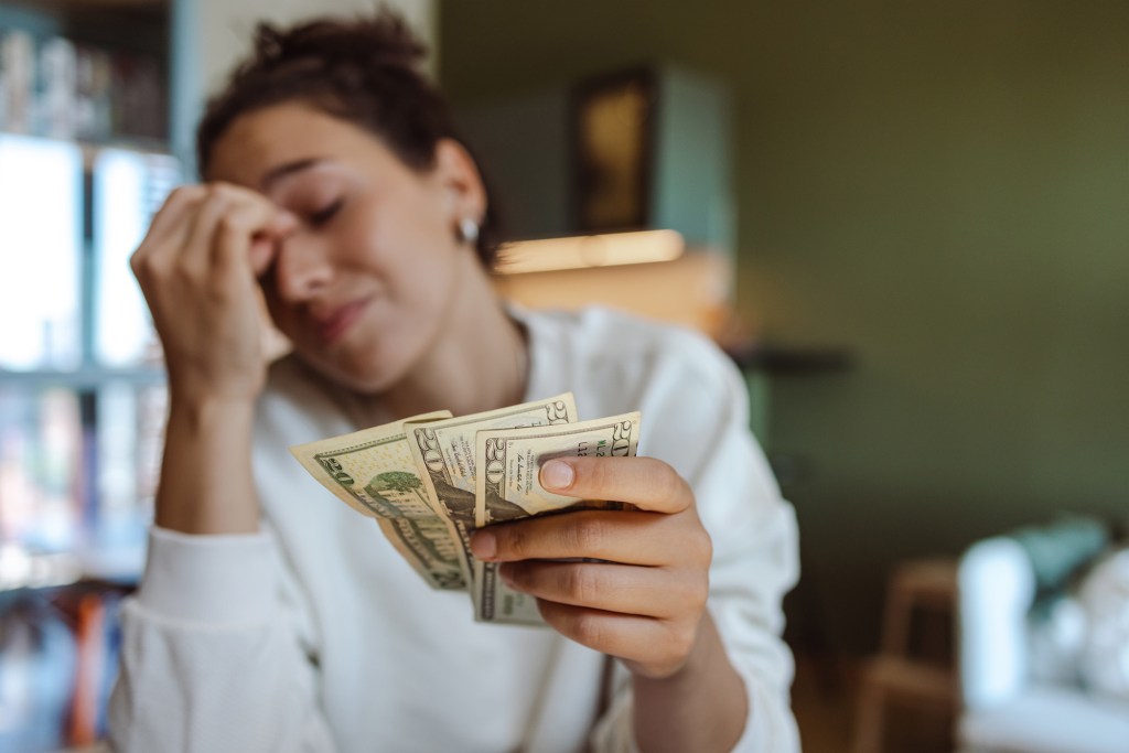 A worried young woman holding money