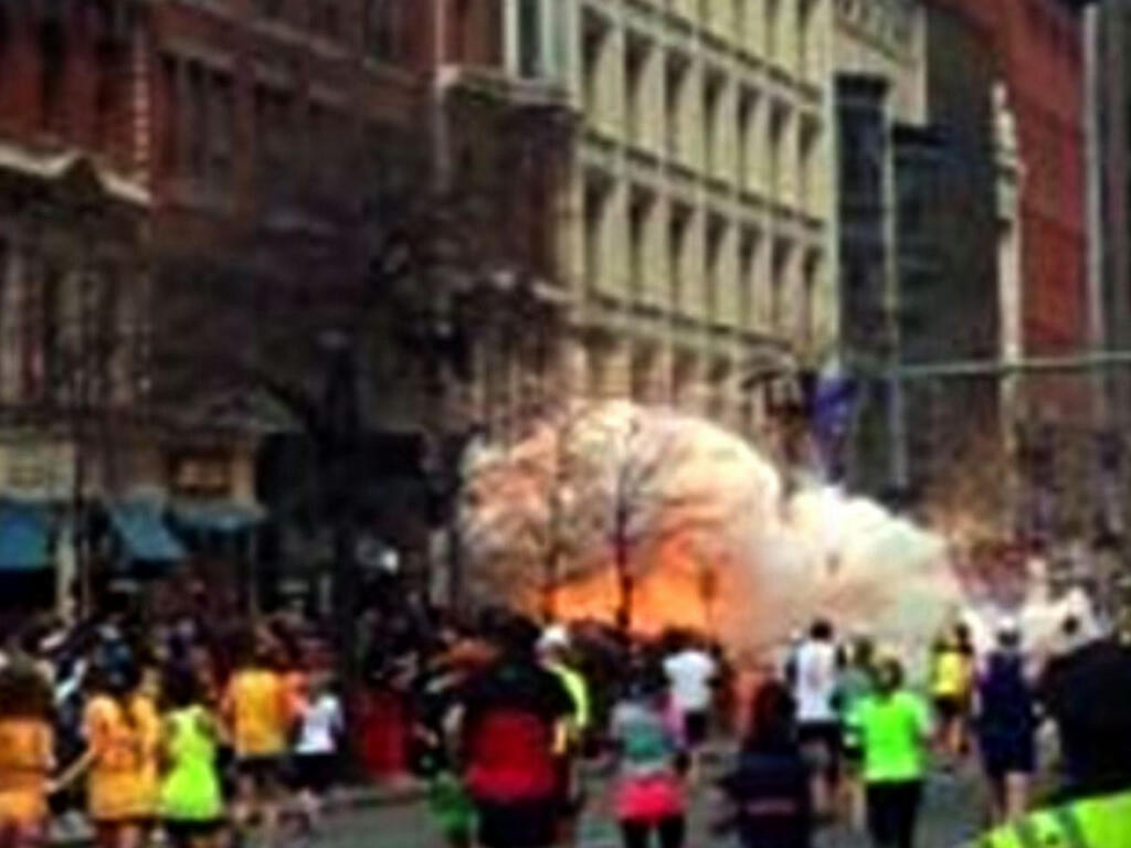 Spectators and runners evade from an explosion near the finish line of the Boston Marathon on April 15, 2013. 