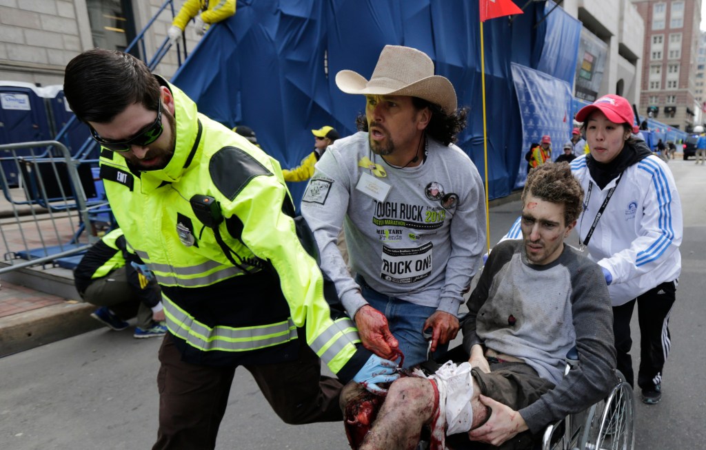 A man is pushed on a wheelchair after he was injured in one of two explosions near the finish line of the Boston Marathon in Boston. 