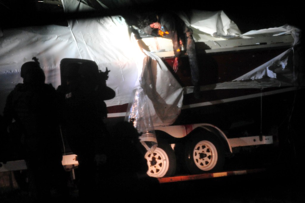 Boston Marathon bombing suspect Dzhokhar Tsarnaev leans over in a boat as law enforcement officials point rifles at him at the time of his capture in Watertown, Mass on April 19, 2013. 