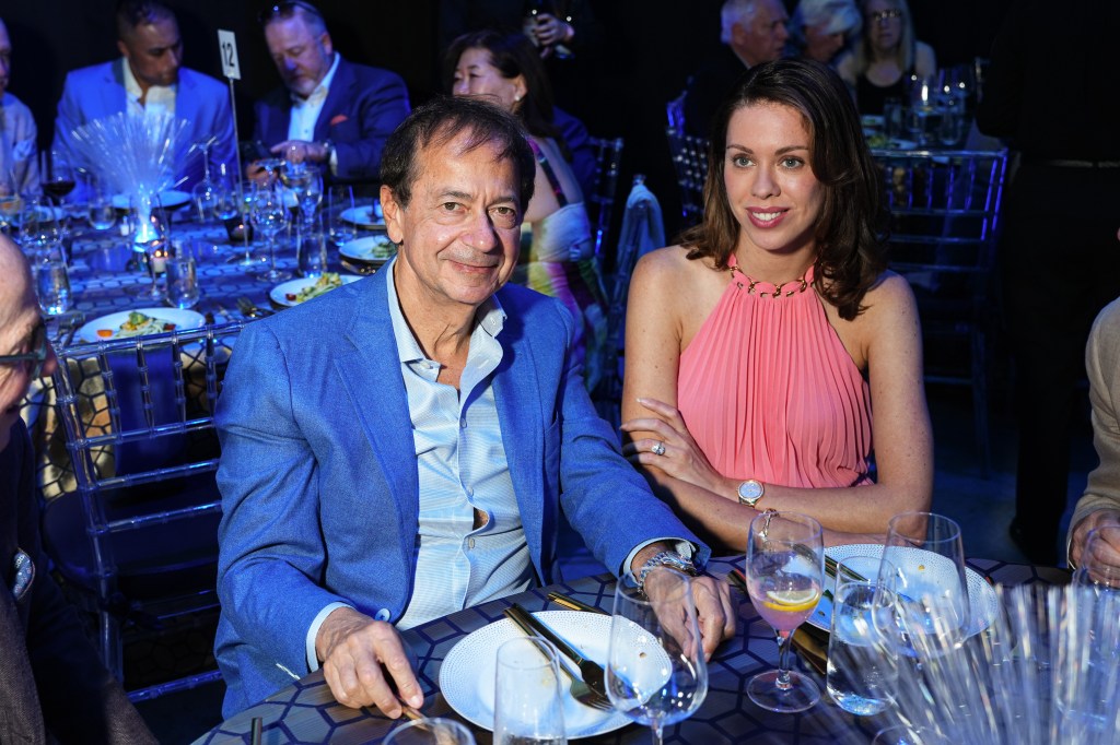 John Paulson (left) and girlfriend Alina de Almeida sitting side by side at a table