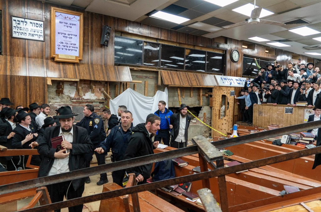 New York Police officers conceal the breach in the wall of the synagogue that led to a tunnel dug by students.