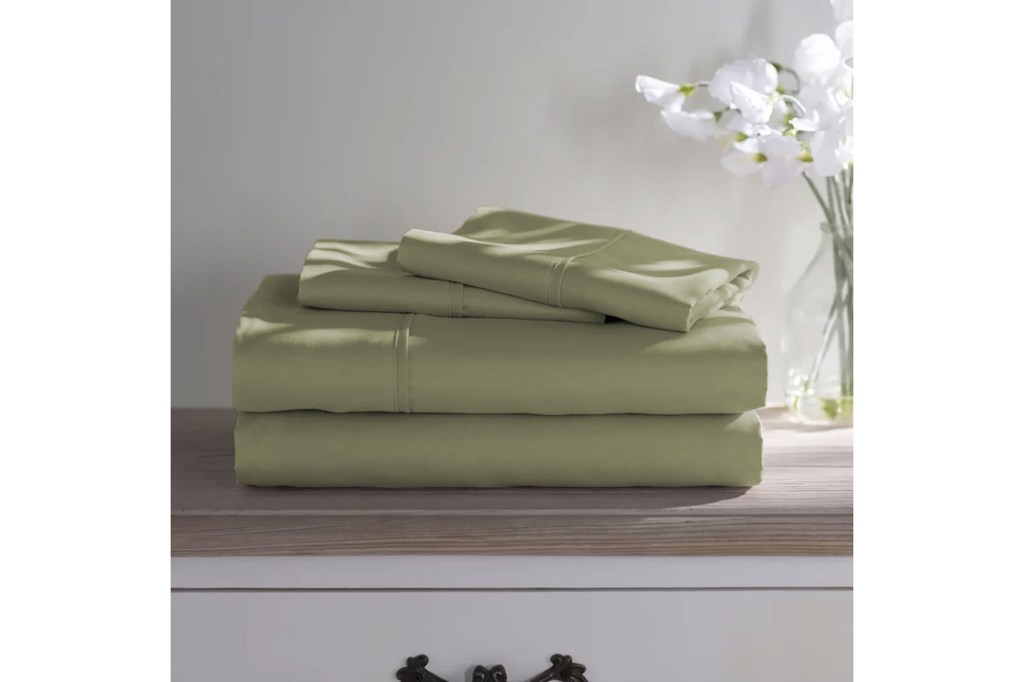 A stack of green sheets from Wayfair Basics® 1800 Series on a dresser