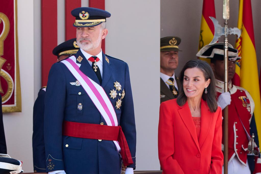 King Felipe of Spain wears full regalia as he stands next to Queen Letizia, in a red suit.