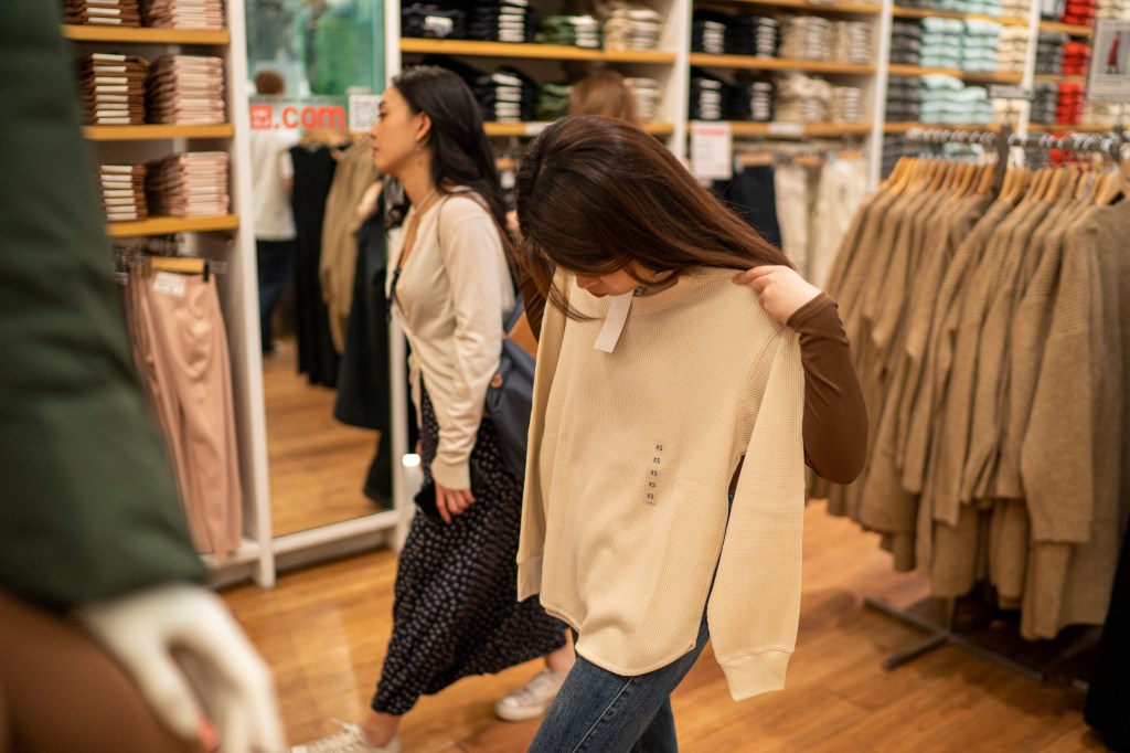 NEW YORK, NY - SEPTEMBER 22: People look at clothing displayed at a Uniqlo store September 22, 2023 in New York City. Uniqlo Company is a Japanese clothing designer, manufacturer and retailer.