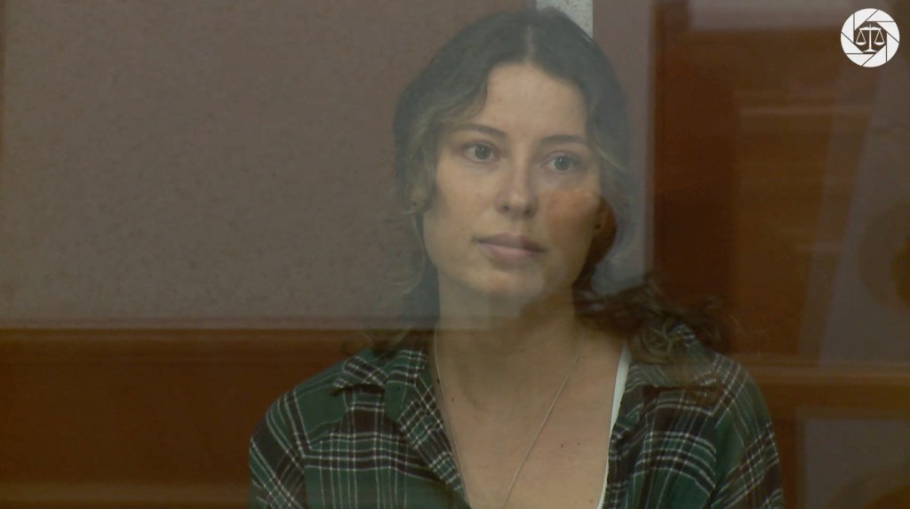 The court in the Urals city of Yekaterinburg published a short video of Ksenia Karelina sitting in a glass cage, wearing jeans and a green plaid shirt.