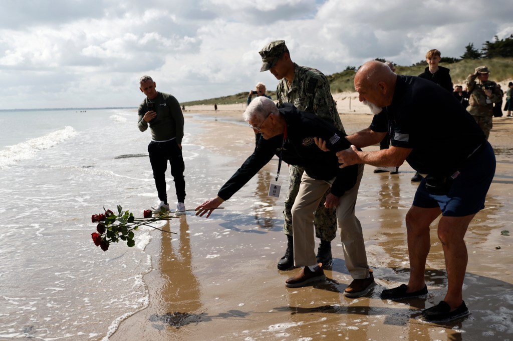 American WWII veteran Bill Wall throws roses into the water during a wreath-laying ceremony at Utah Beach, Wednesday, June 5, 2024 at Utah Beach, Normandy,. World War II veterans from across the United States as well as Britain and Canada are in Normandy this week to mark 80 years since the D-Day landings that helped lead to Hitler's defeat.