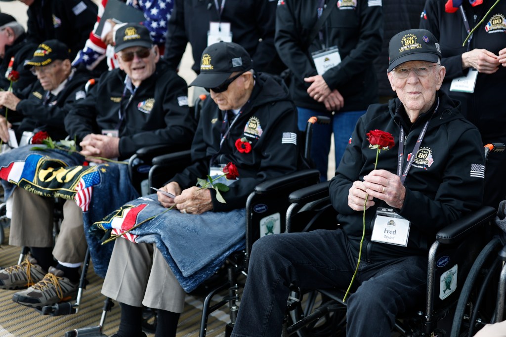 American WW II veteran Fred Taylor, right, and others hold roses