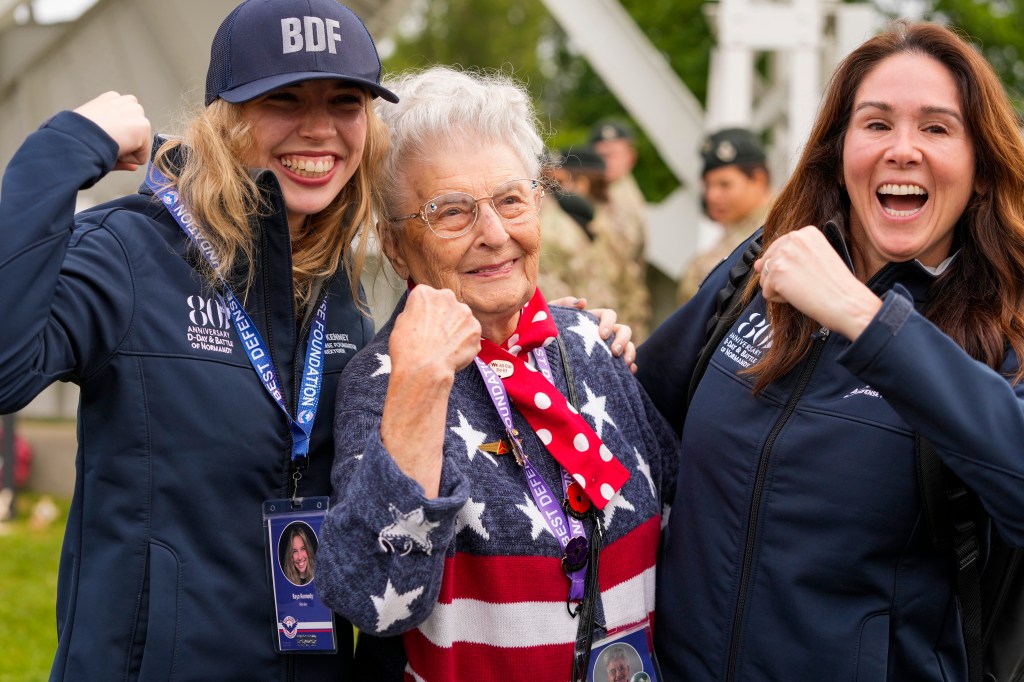 Anna Mae Krier, also known as a Rosie the Riveter, center, poses during a service at the Pegasus Bridge memorial in Benouville, Normandy, France, Wednesday, June 5, 2024. 