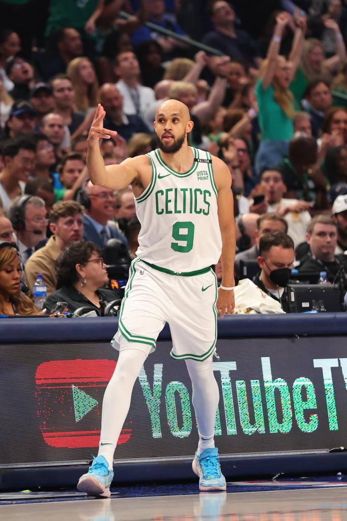 Derrick White of the Boston Celtics reacts to scoring a three-point basket in Game Four of the 2024 NBA Finals against the Dallas Mavericks, with spectators in the background.