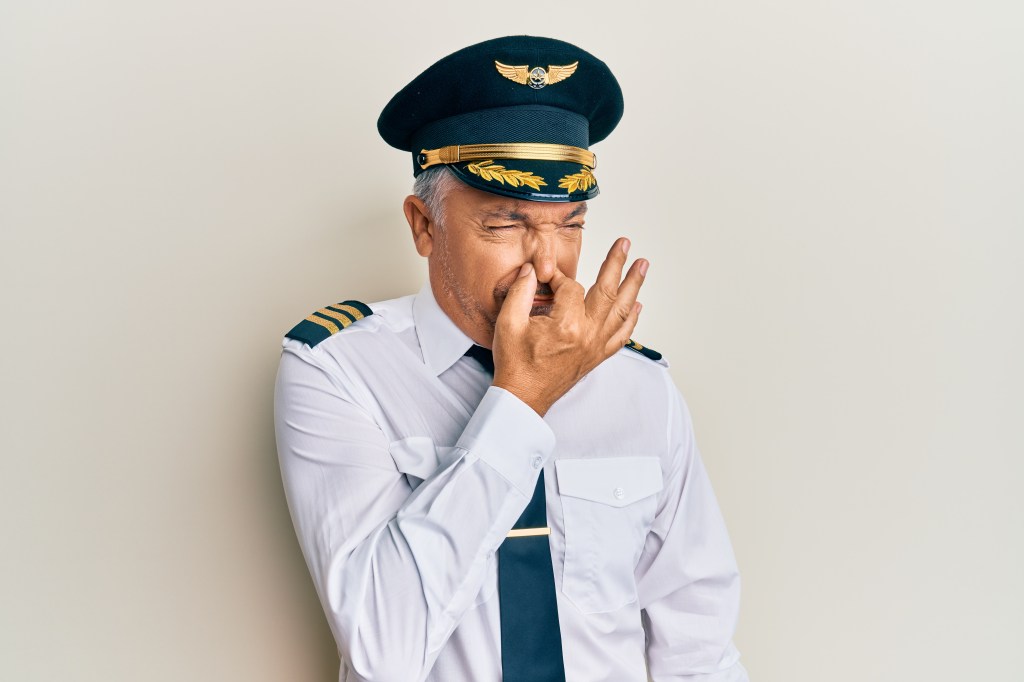 airplane pilot in uniform smelling something stinky 