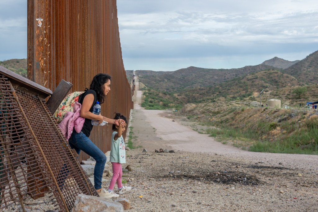 A migrant family crosses through border fencing into the U.S.