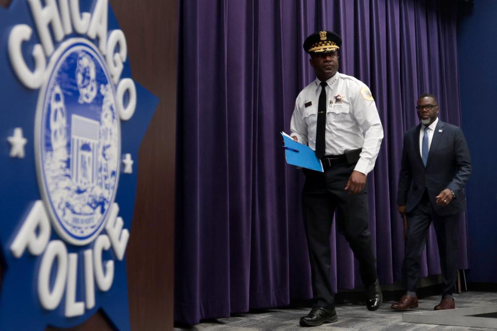 Brandon Johnson walking on stage with a uniformed member of the Chicago Police Department.