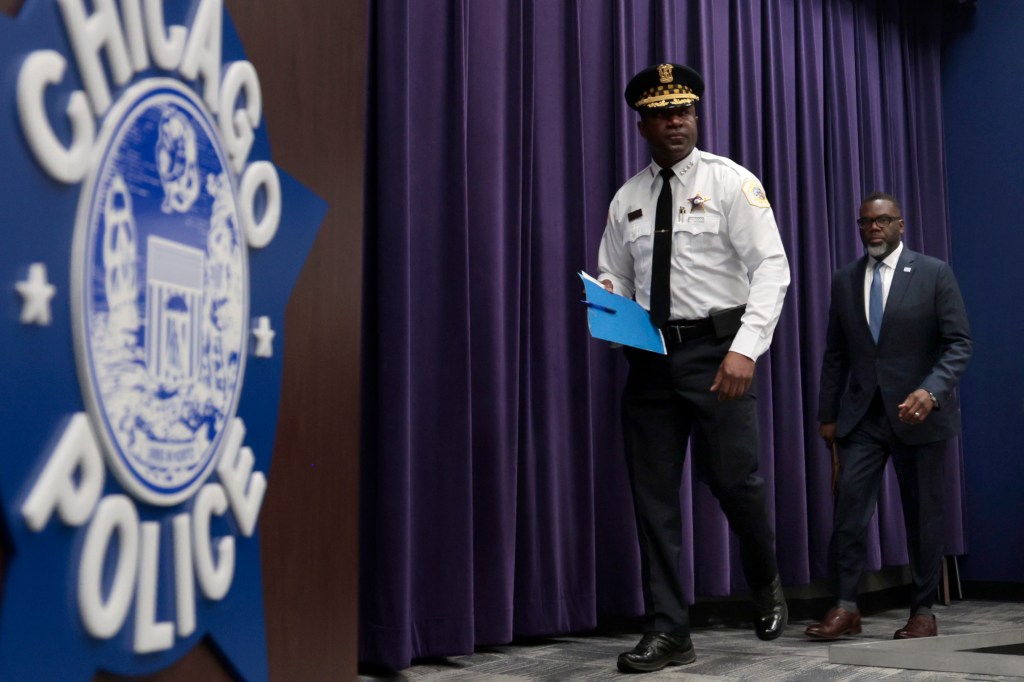 Brandon Johnson walking on stage with a uniformed member of the Chicago Police Department.