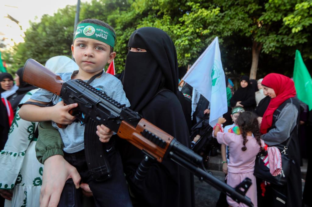 Hamas supporters armed a child with a rifle during a demonstration over Haniyeh's assassination.