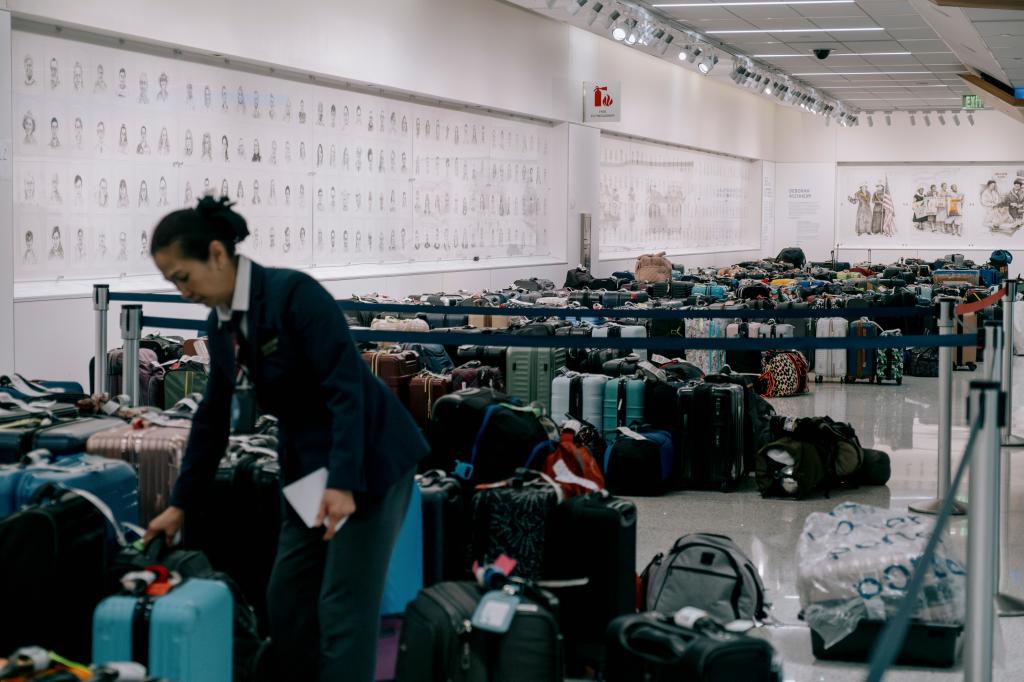 Delta employee organizes lots of luggage at baggage claim.