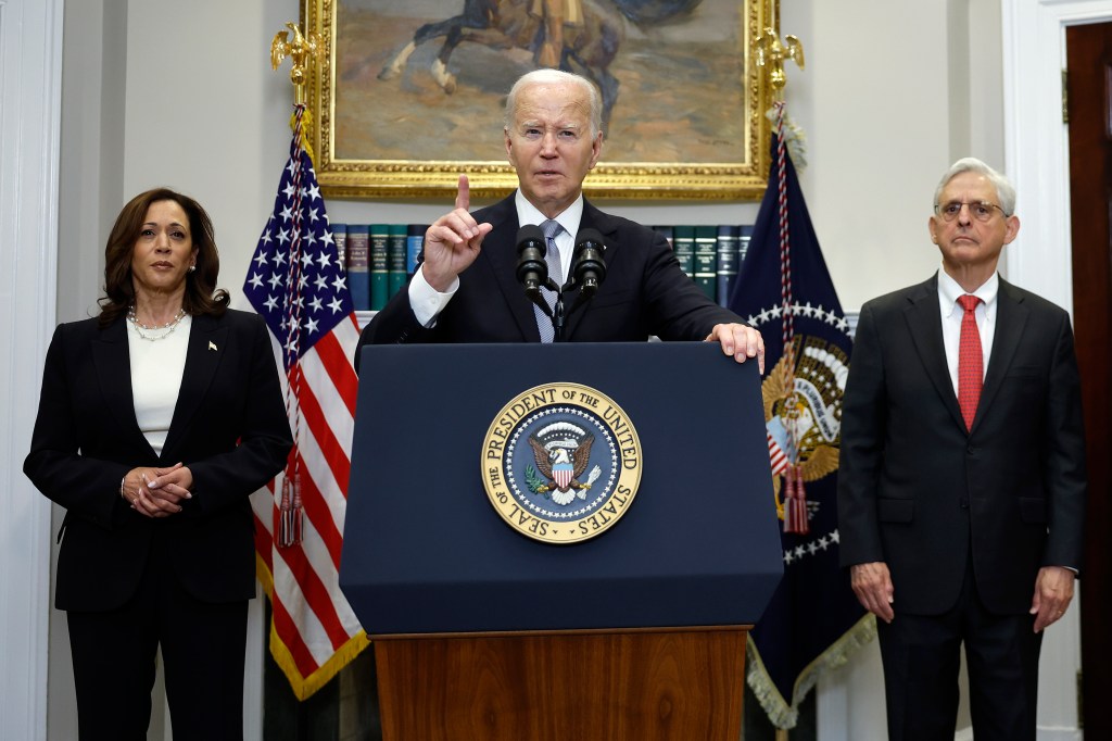 U.S. President Joe Biden, Vice President Kamala Harris, and Attorney General Merrick Garland standing together, with Biden addressing the assassination attempt on former President Donald Trump from a podium.