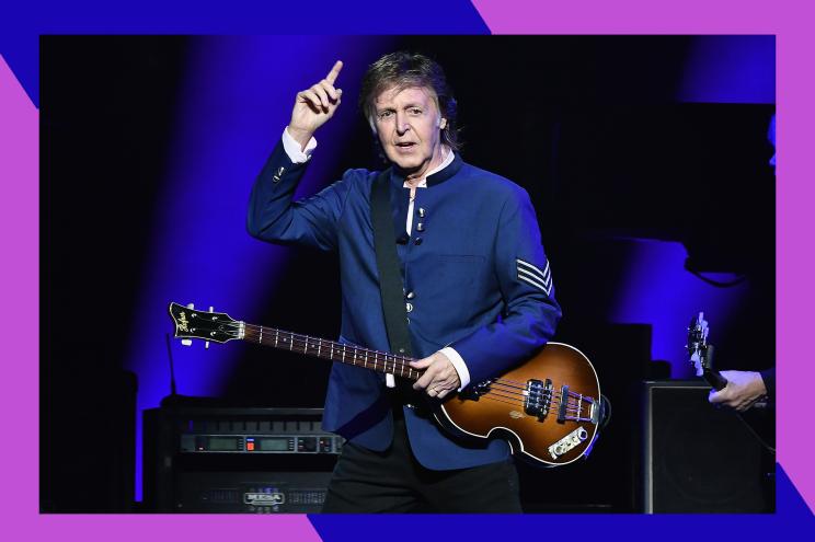 Paul McCartney gestures to the crowd with his guitar in hand.