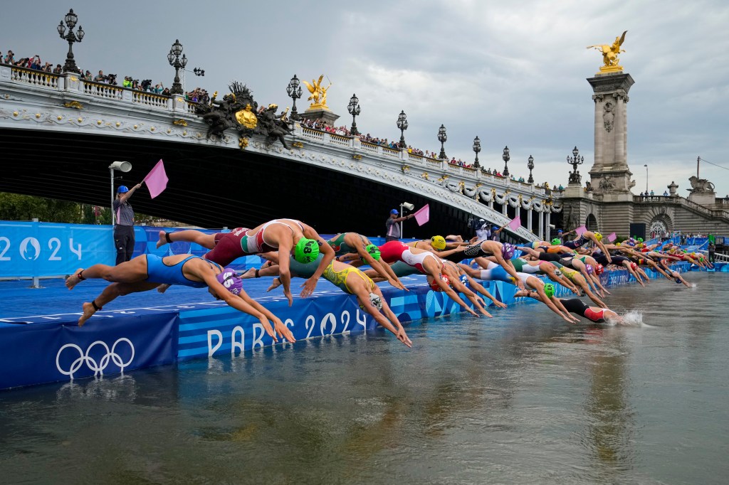 Competitors dive into the Seine at the start of the women's triathlon at the Paris 2024 Olympic Games on July 31, 2024.