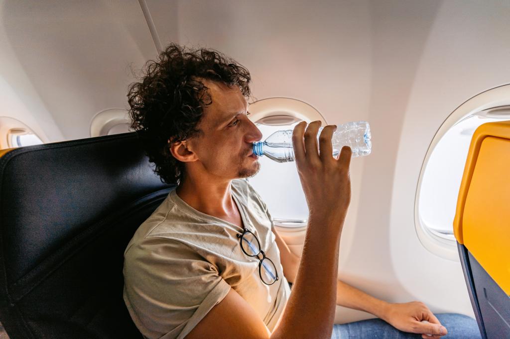 young man drinking water in an Airplane