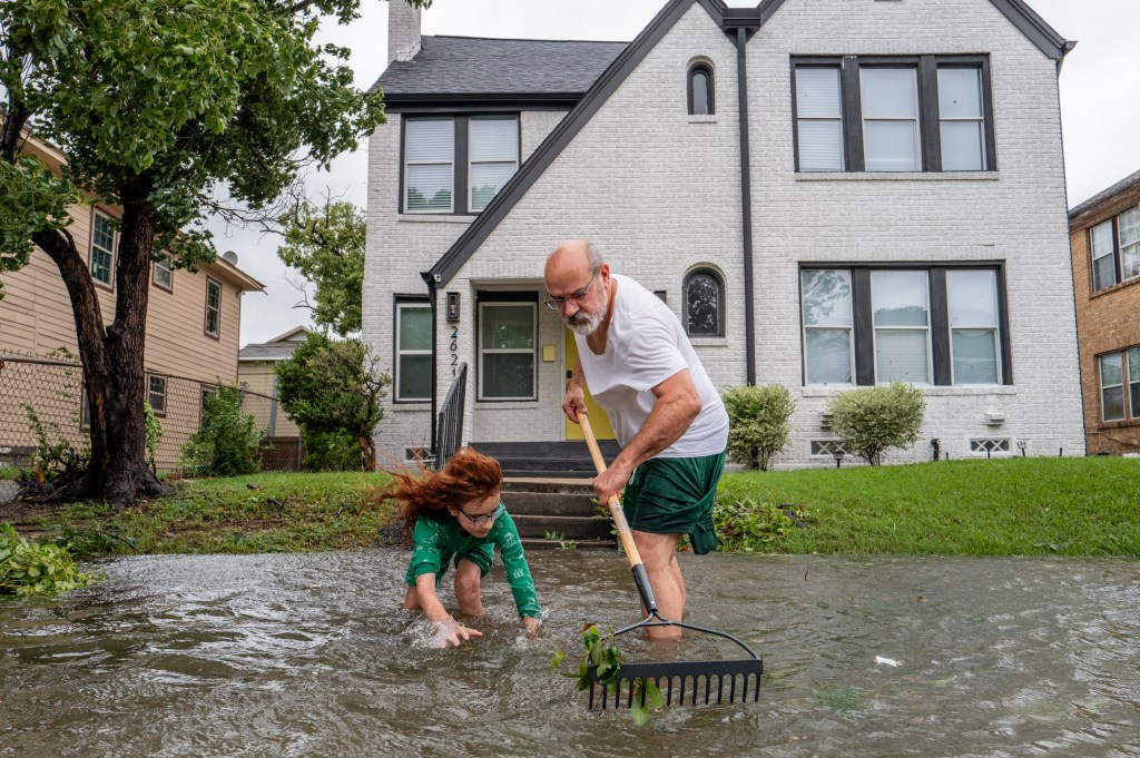 Houston resident Jack Reyna and his son work to drain the floodwaters outside their home.