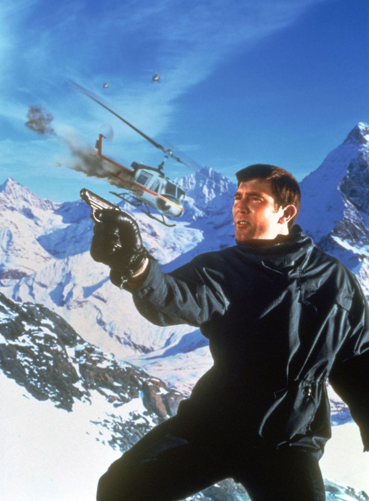 George Lazenby holding a gun as James Bond.