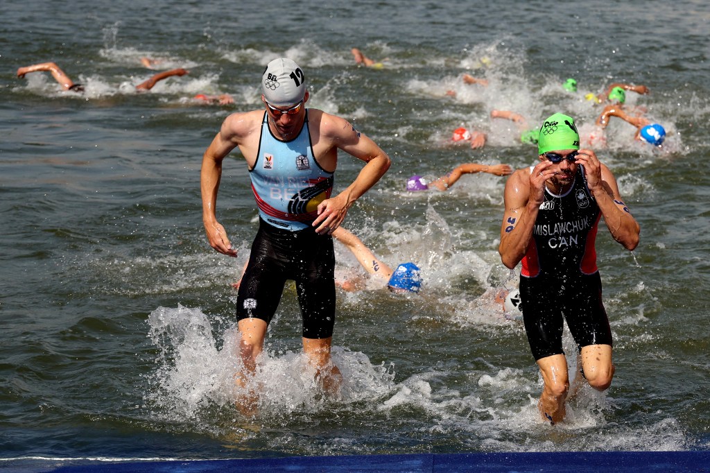  Marten van Riel of Team Belgium and Tyler Mislawchuk of Team Canada compete during the men's triathlon on July 31, 2024.