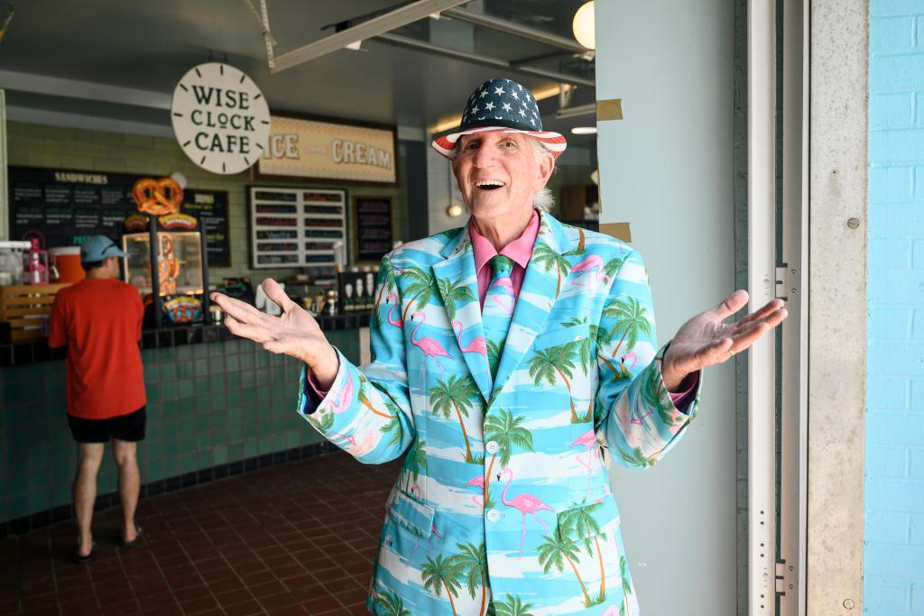 Owen Loof, the Best Dressed Man in Rockaway, performing standup comedy in a turquoise suit with pink flamingos and palm trees on the boardwalk at Rockaway Beach, Queens, NY