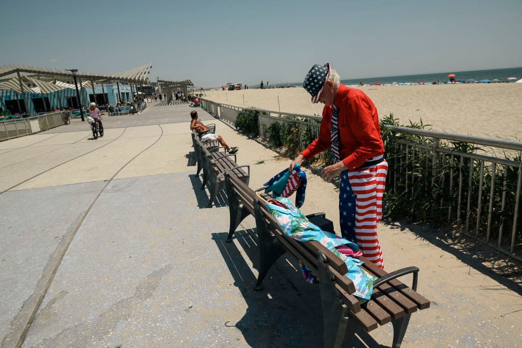 Owen Loof, the best dressed man in Rockaway, sitting on a bench by the boardwalk and beach, wearing red and white striped pants