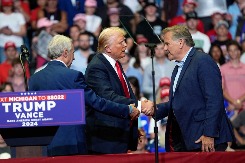 Former President Donald Trump shaking hands with Michigan Senate candidate, Mike Rogers, at a campaign rally in Grand Rapids, Michigan, 2024