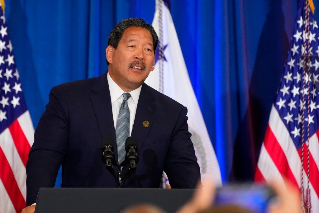 Seattle Mayor Bruce Harrell standing at a podium with microphones, giving remarks at an event with Vice President Kamala Harris in McKinstry, Seattle.