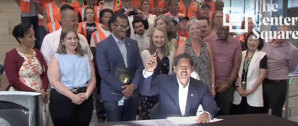 Geraldine Fraser-Moleketi, Marcel Dionne, and Ryan Frazier standing with a group of people, discussing the proposed $1.55 billion transportation levy in Seattle.