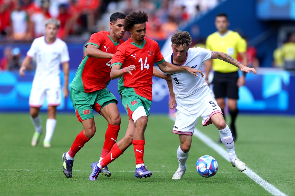 Griffin Yow of Team United States in a football duel with Oussama Targhalline and Achraf Hakimi of Team Morocco during the Men's Quarter Final match at the Olympic Games Paris 2024