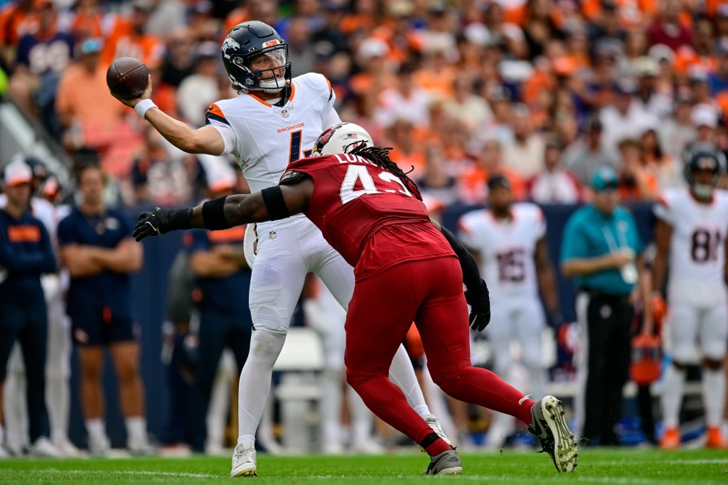 Zach Wilson #4 of the Denver Broncos is pressured by Jesse Luketa #43 of the Arizona Cardinals in the first quarter during the preseason game at Empower Field at Mile High on August 25, 2024 in Denver, Colorado. 