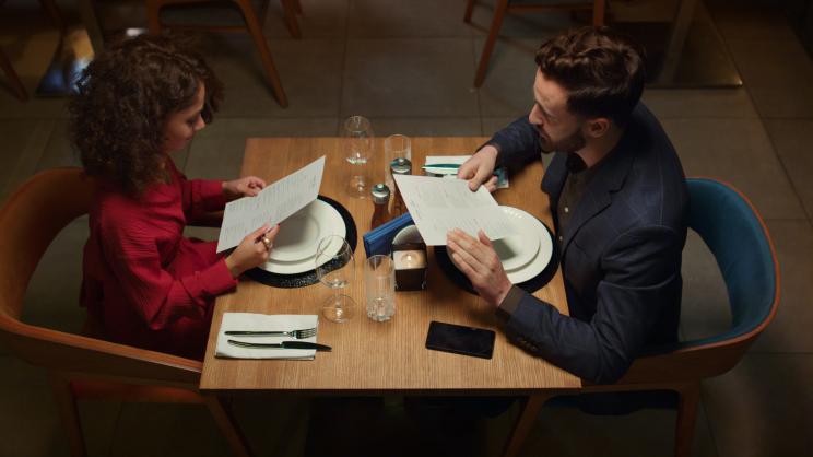 Attractive couple looking at a menu during a romantic dinner in a fancy restaurant at night