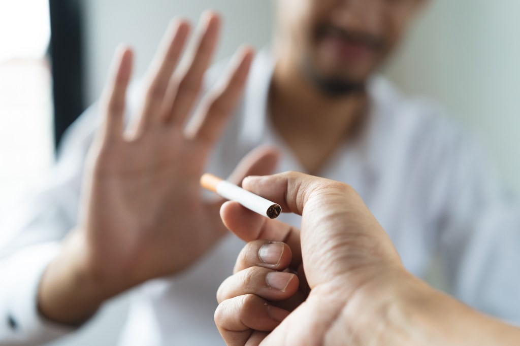 Close up hands of person refusing to smoke cigarette when offered.