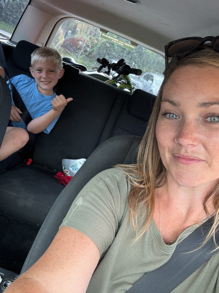 Jay Whitfield sitting in a car with her seven-year-old son, both looking at screens