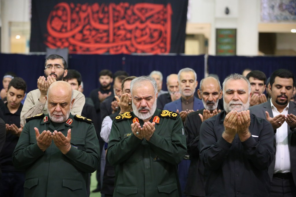 General Ali Fadavi, deputy commander of Iran's Revolutionary Guard Corps, leading prayers at a memorial ceremony for Ismail Haniyeh, the deceased Hamas leader, in Tehran, Iran, surrounded by other leaders.