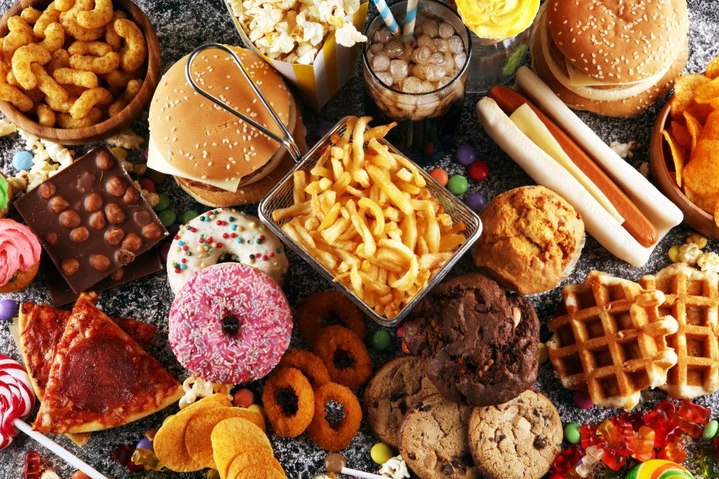 Assortment of unhealthy food products including fries and cola on a table