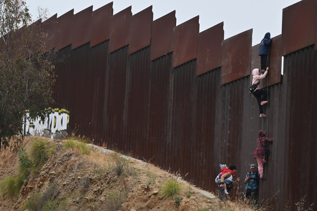  A group of adult and child migrants are smuggled at the Tijuana-San Diego border, as they climb the wall to seek asylum to the United States.