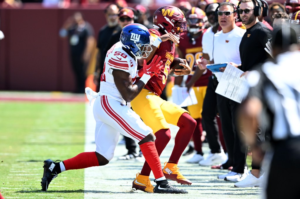 Bobby Okereke #58 of the New York Giants forces quarterback Jayden Daniels #5 of the Washington Commanders out of bounds