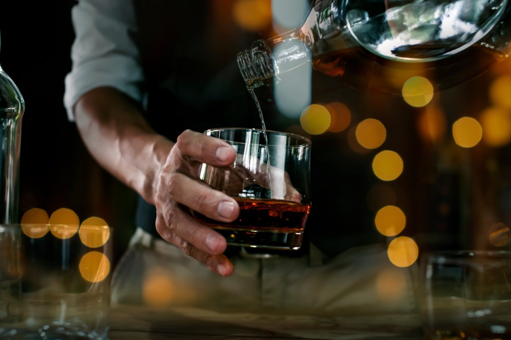 Close up of male bartender pouring drink for customer at a bar