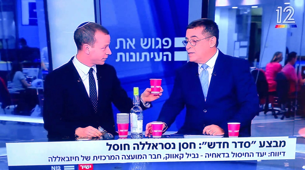 Amit Segal (left) of News 12 cracked open a bottle of arak, a popular Middle Eastern liquor, and handed a cup to fellow News 12 panelist Ben Caspit (right).